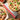 Image shows a pizza cut into six pieces with the soft-grip rocking pizza cutter underneath. There is another uncut pizza in the bottom left corner.