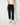 Black jogger pant with beige top and sneakers against a white wall