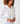 Close up image of the model wearing Tuxedo Ruffle shirt. The top button is unbuttoned, and she has her hands in front of her. She is wearing several gold colored bracelets.