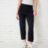 Black jogger pant with beige top and sneakers against a white wall
