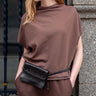 Mersea Frenchie Dolman Neck Top in Espresso. Model has paired it with similar colored pants and a little purse