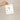 Hand holding a plantable seed paper envelope with illustrations on a beige background