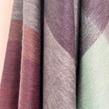 Close-up of fabric swatches in purple, gray, and green on a beige background