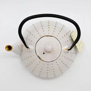 White ceramic teapot with black handle and gold accents on a white background