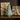 LED Decorative Christmas tree candle between two wrapped gifts on a wooden surface.